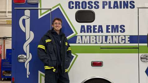 Anthony Lange stands wears EMS gear and stands in front of an ambulance.