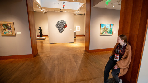 Hoppe sits on a stool between two gallery spaces in the Chazen Museum of Art.