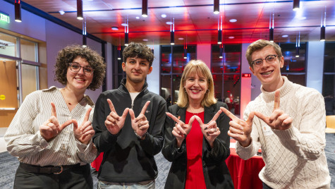 Four people pose for the camera as their fingers form Ws.
