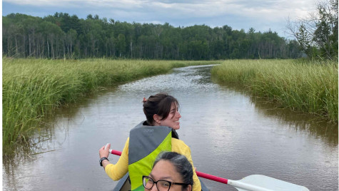 Becca Honeyball and Ashla Ojibway sit in a canoe among manoomin, or wild rice, beds.