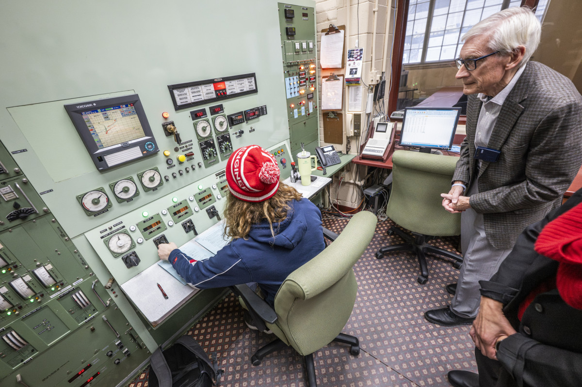 Governor Evers watches as an undergraduate student operates the nuclear reactor panel.