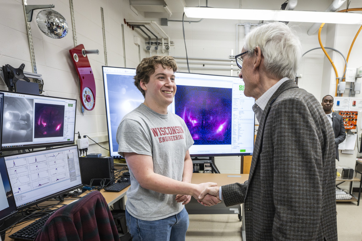 Gergen and Evers shake hands in a science lab.