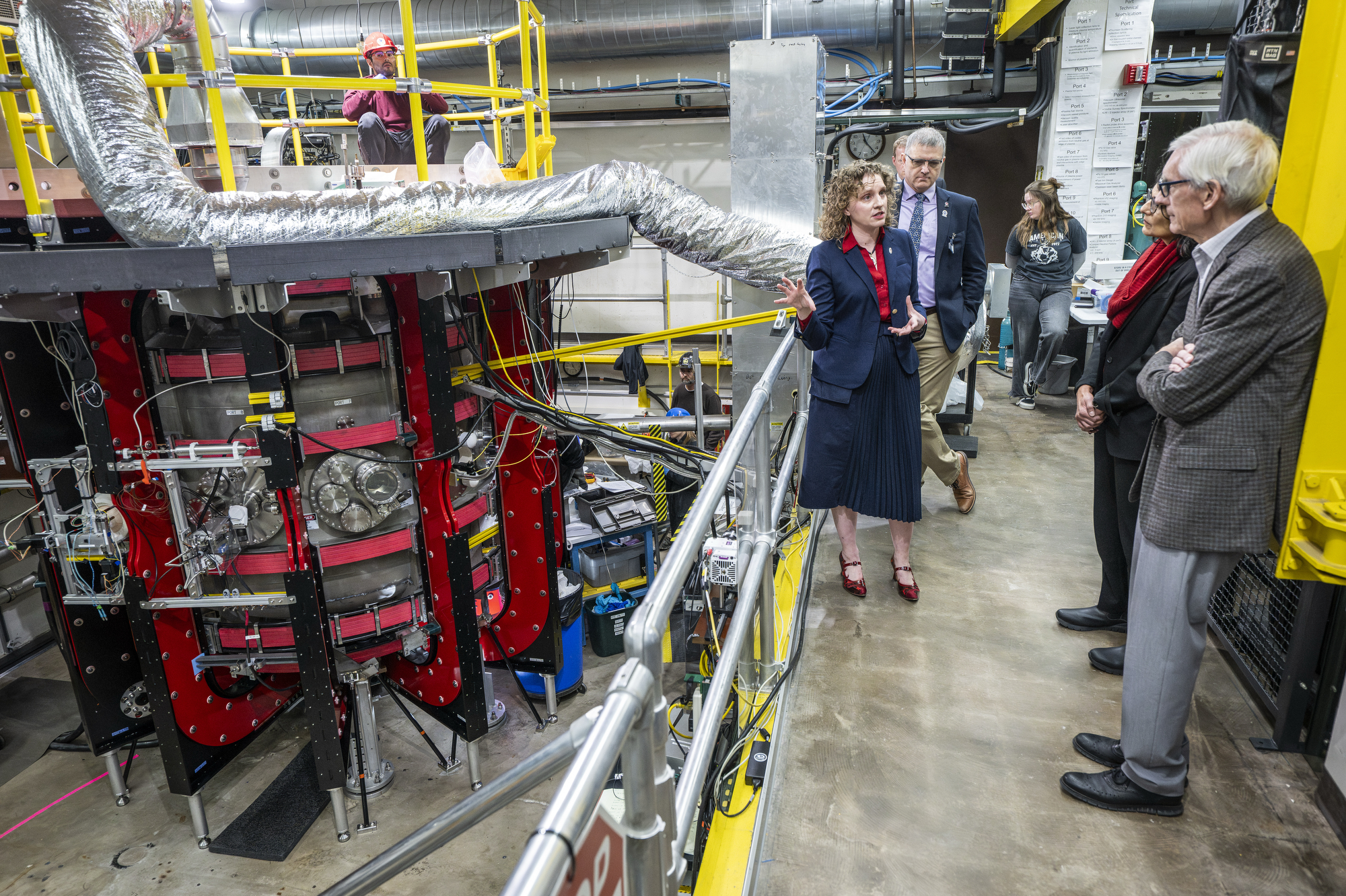 Diem speaks to a group that stands on a mezzanine that overlooks the Pegasus-III experiment equipment.
