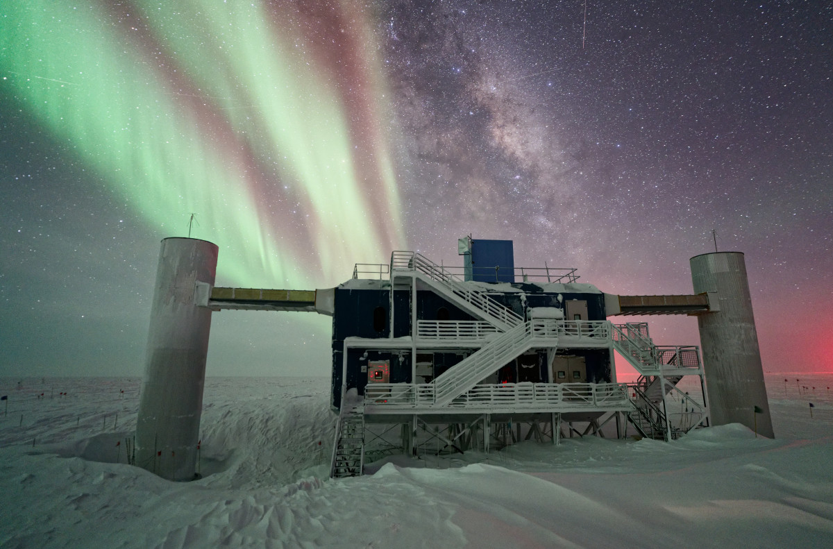 The IceCube Laboratory with auroras and the Milky Way in the background.