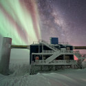 The IceCube Laboratory with auroras and the Milky Way in the background.