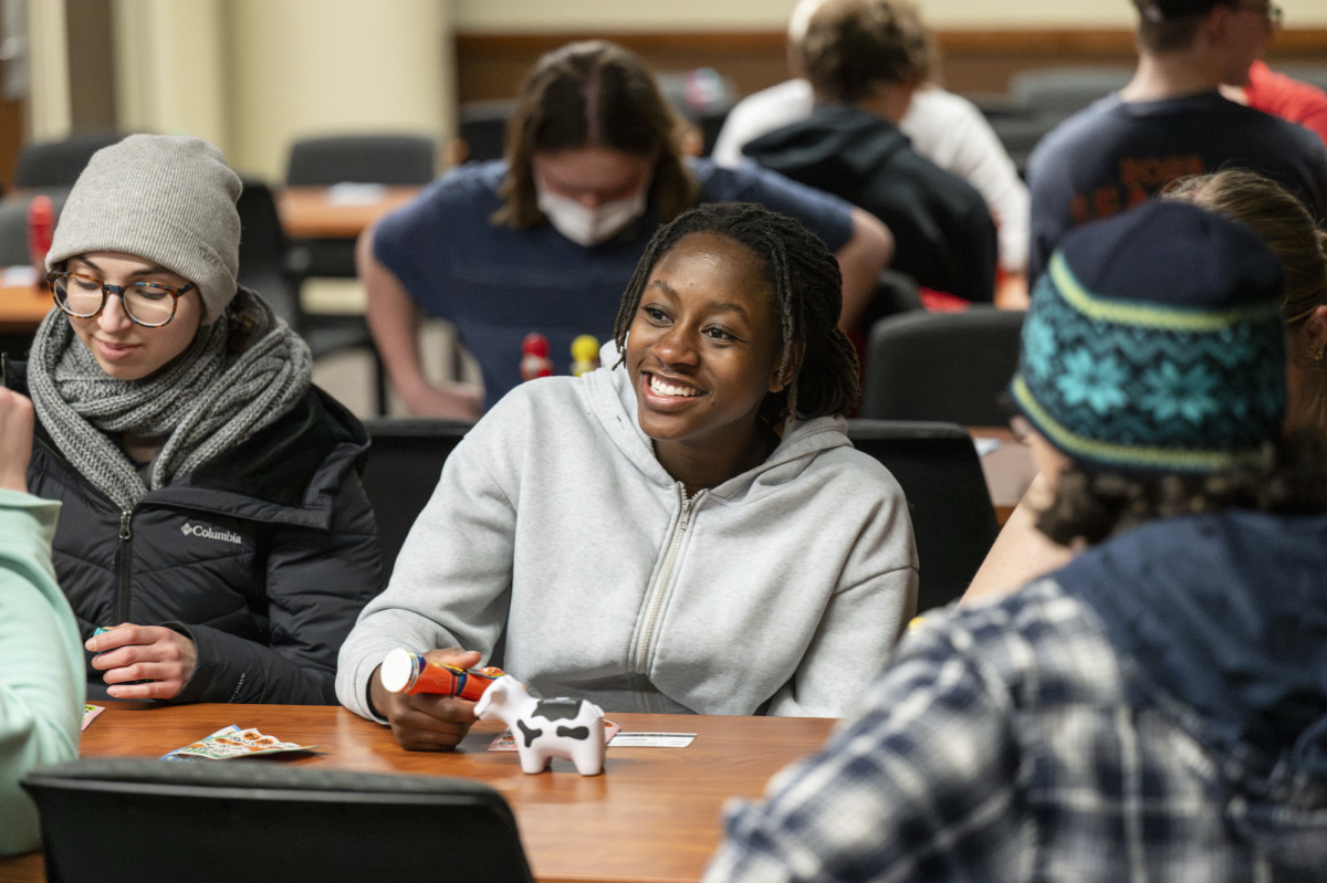 A woman sitting at a table with others playing a game of bingo smiles.