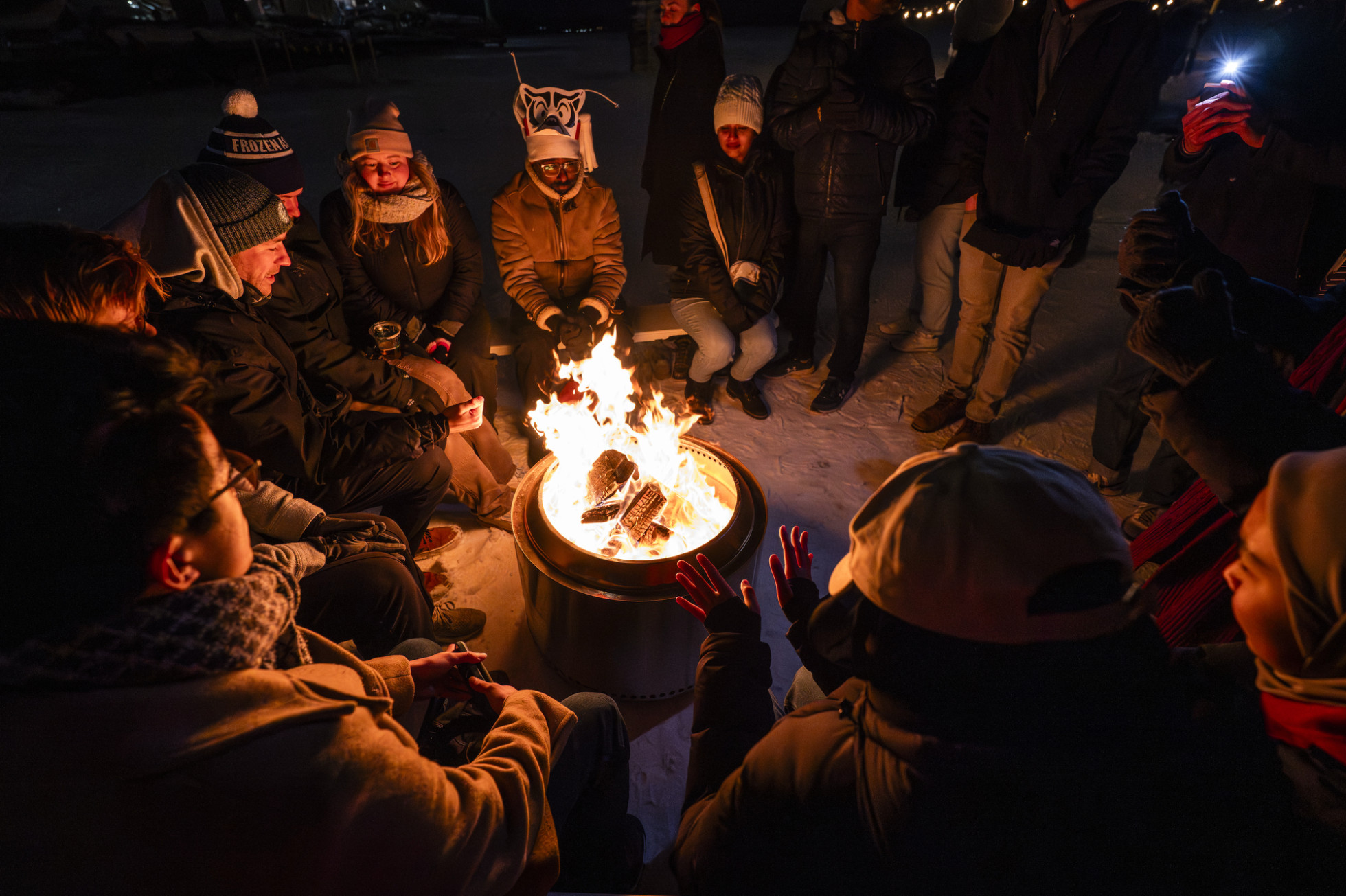 People gather and warm their hands around a portable campfire on the frozen Lake Mendota.