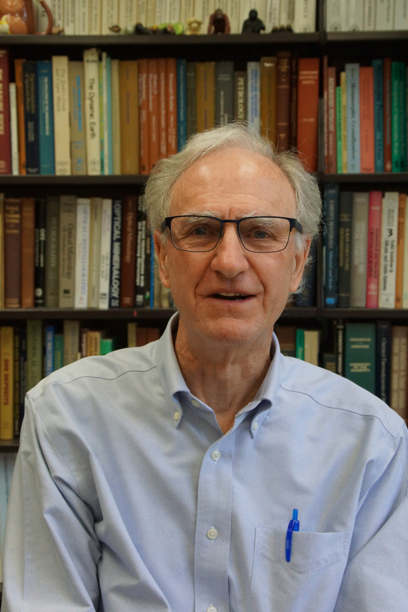 Photo of John Valley in front of a bookcase.