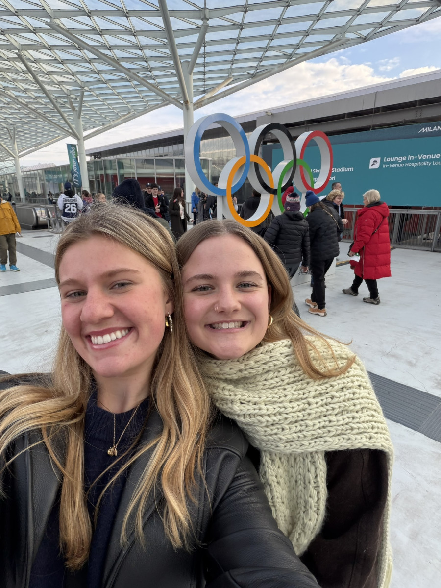 UW student Delaney Kuny and a friend smile for a selfie in front of the Olympic symbol.