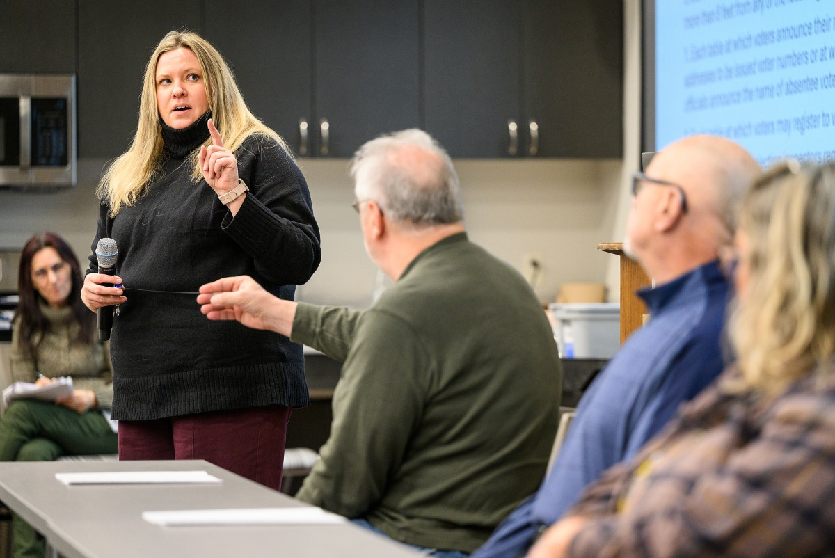Kono Melissa stands in a room of seated Wisconsin residents. She holds a microphone in one hand while answering a question from the crowd.