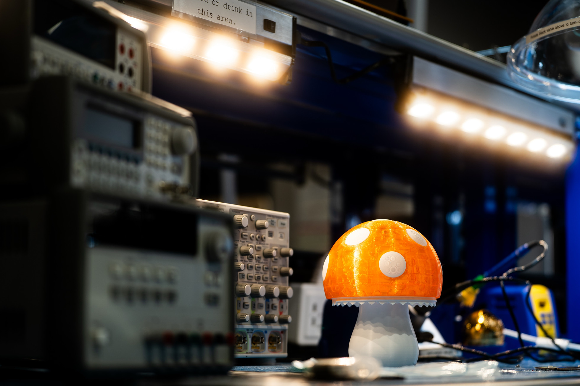 A small mushroom-style lamp on a table, next to electronic equipment.