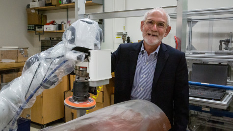 A portrait of Robert Radwin in a suit, next to robotic equipment