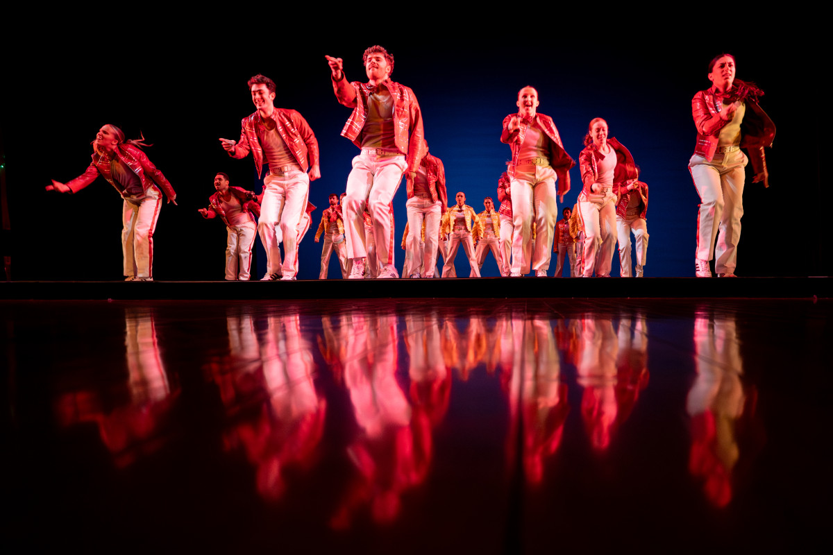 Students perform a choreographed dance as a group on a stage.
