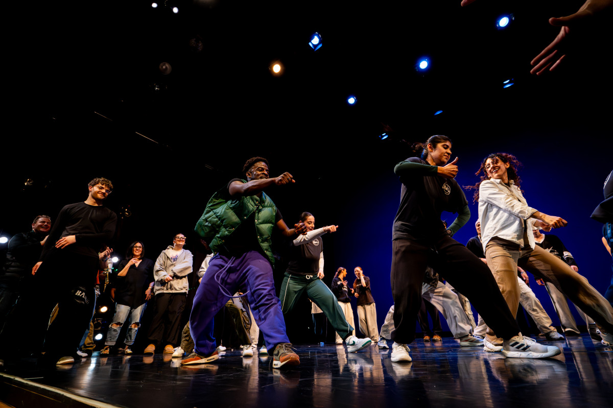 Students freestyle dance as a group on a stage.