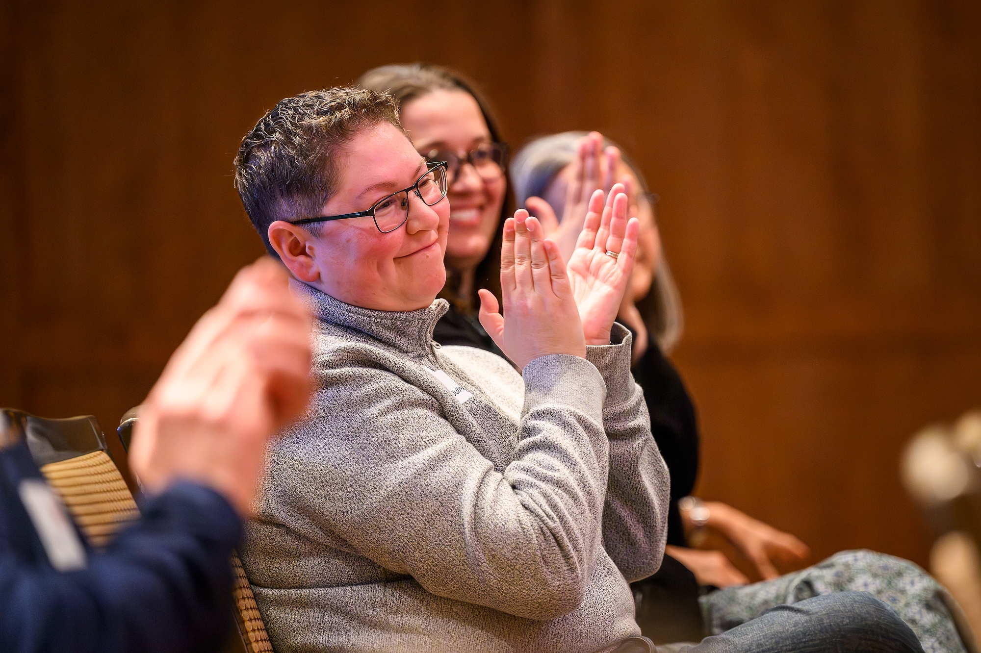 Two people smiling while clapping in a workshop audience