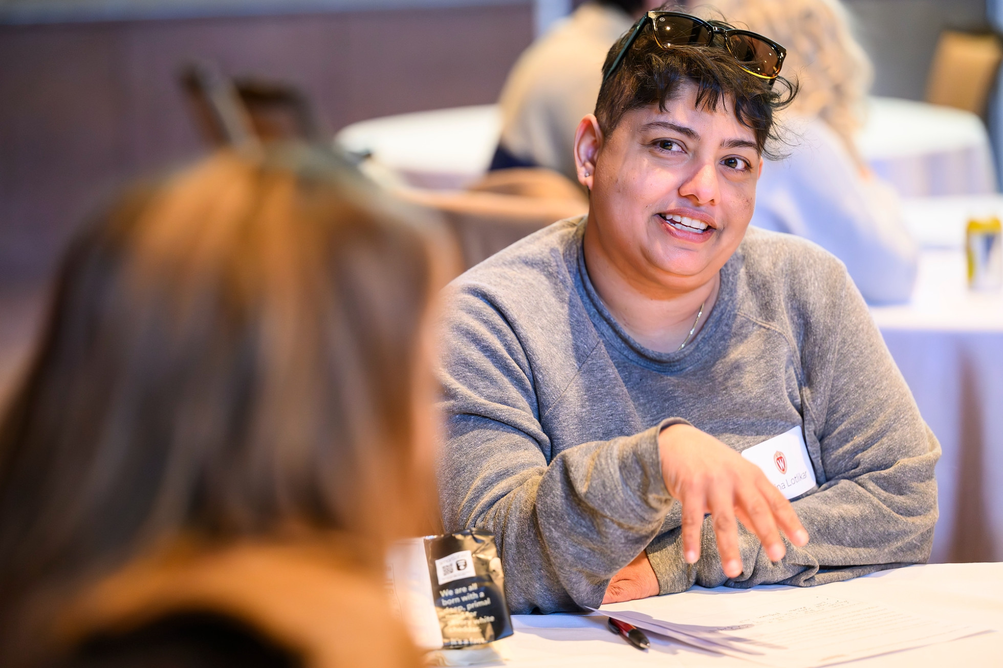 Workshop participant Sarina Lotlikar gesturing while talking to another person at a workshop table