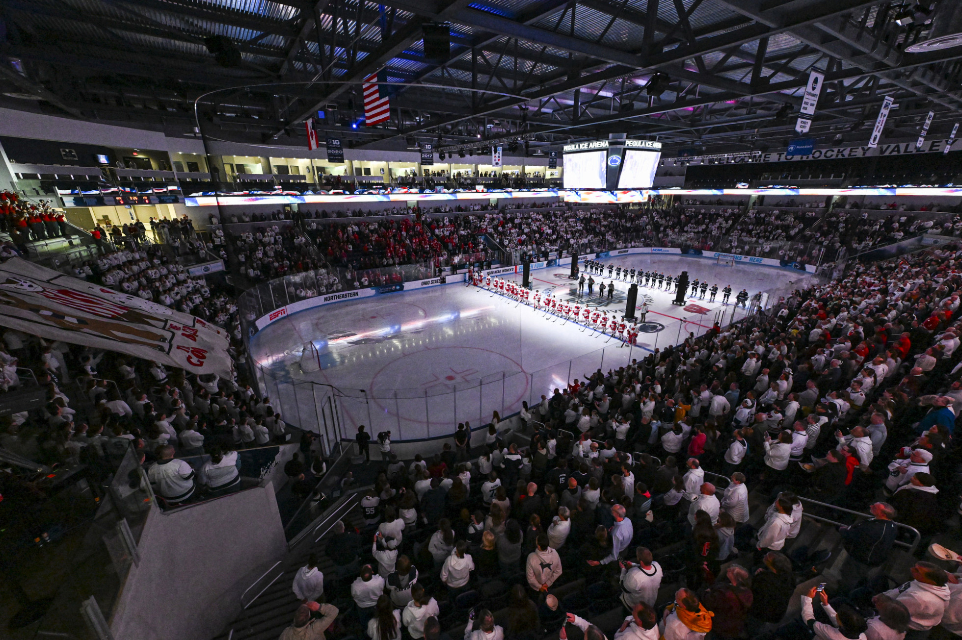 From the stands, crowds stand for the national anthem while both hockey teams – the UW Badgers and Penn State Nittany Lions – stands in line on the ice to honor the American Flag.  