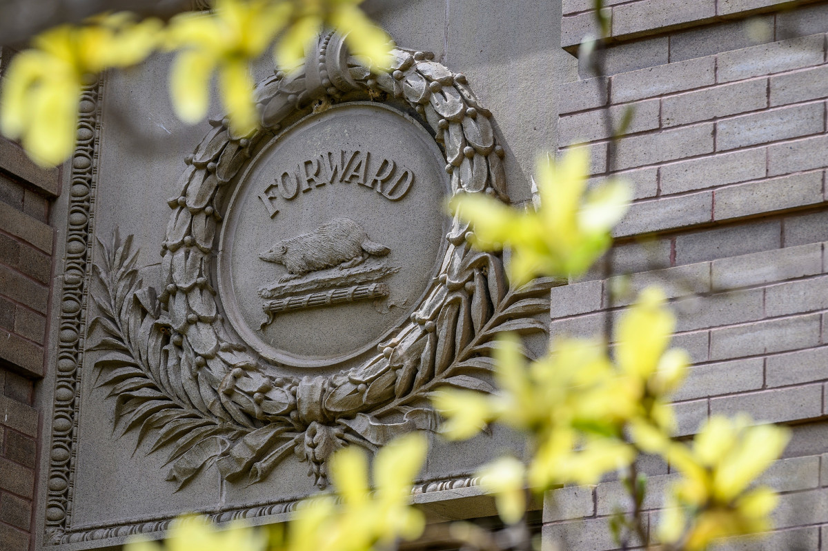 Photo of a stone-carved laurel wreath with a badger and the word Forward in the center