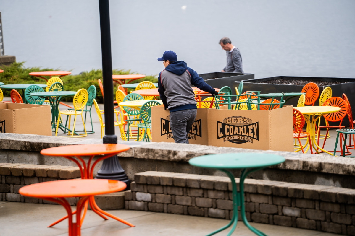 Two workers pull a box and set out chairs at the Memorial Union Terrace.