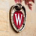 UW–Madison crest logo on the side of a building with red leaves peeking into the top of the photo.