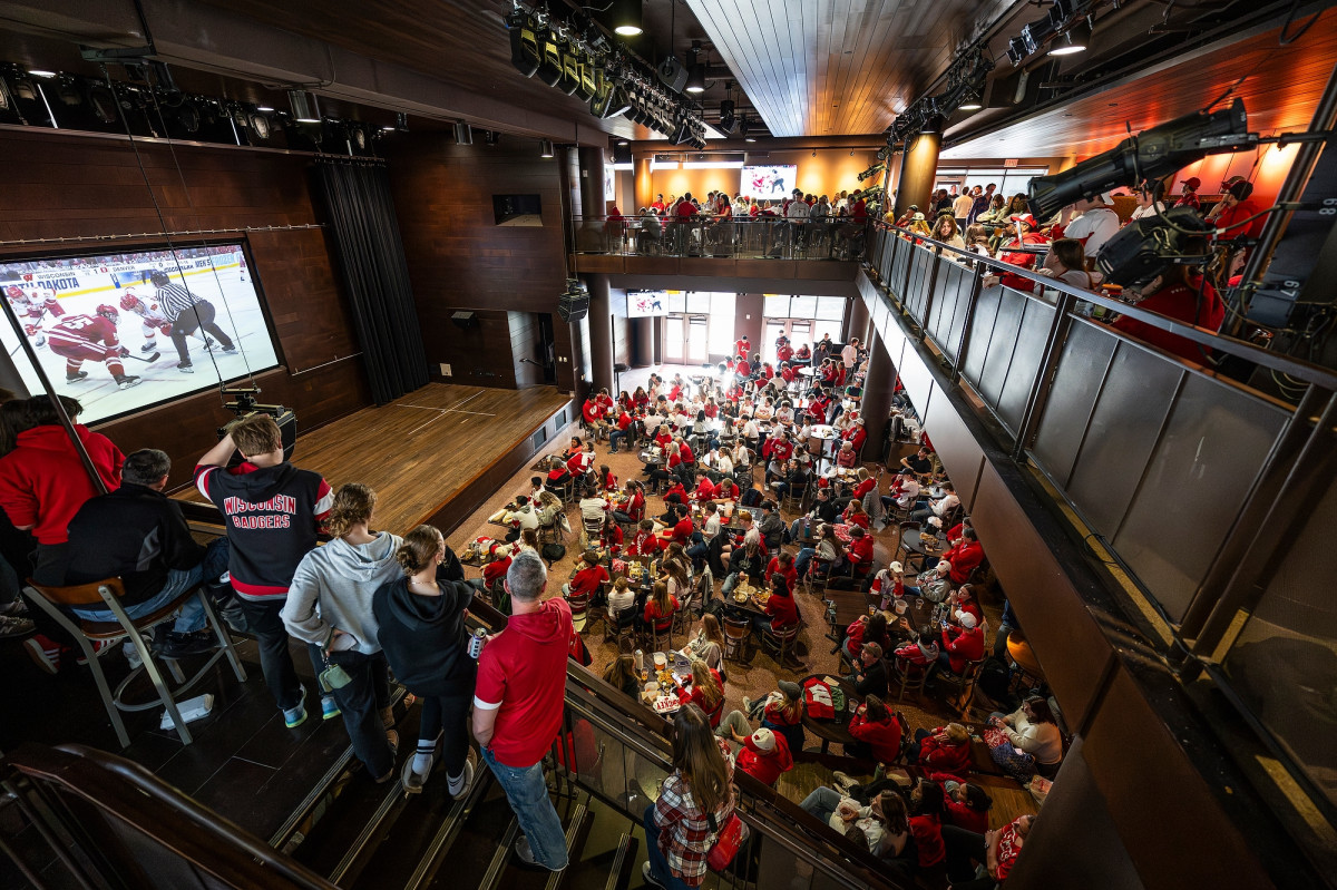 A crowd has gathered to watch the game on a huge screen in a two-tiered music hall.
