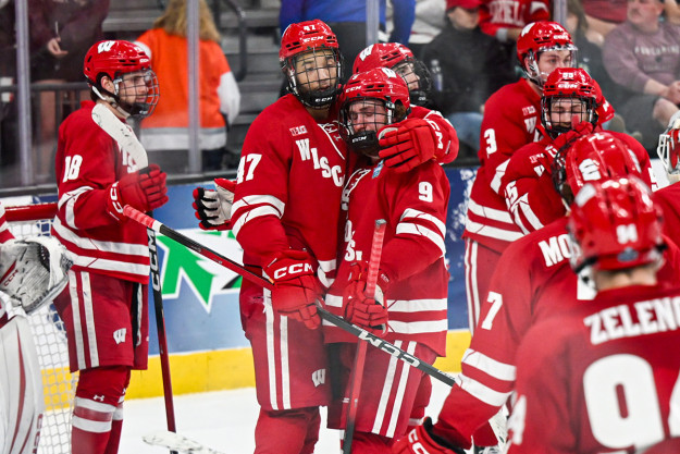 Wisconsin players in red gather and hug each other in defeat.