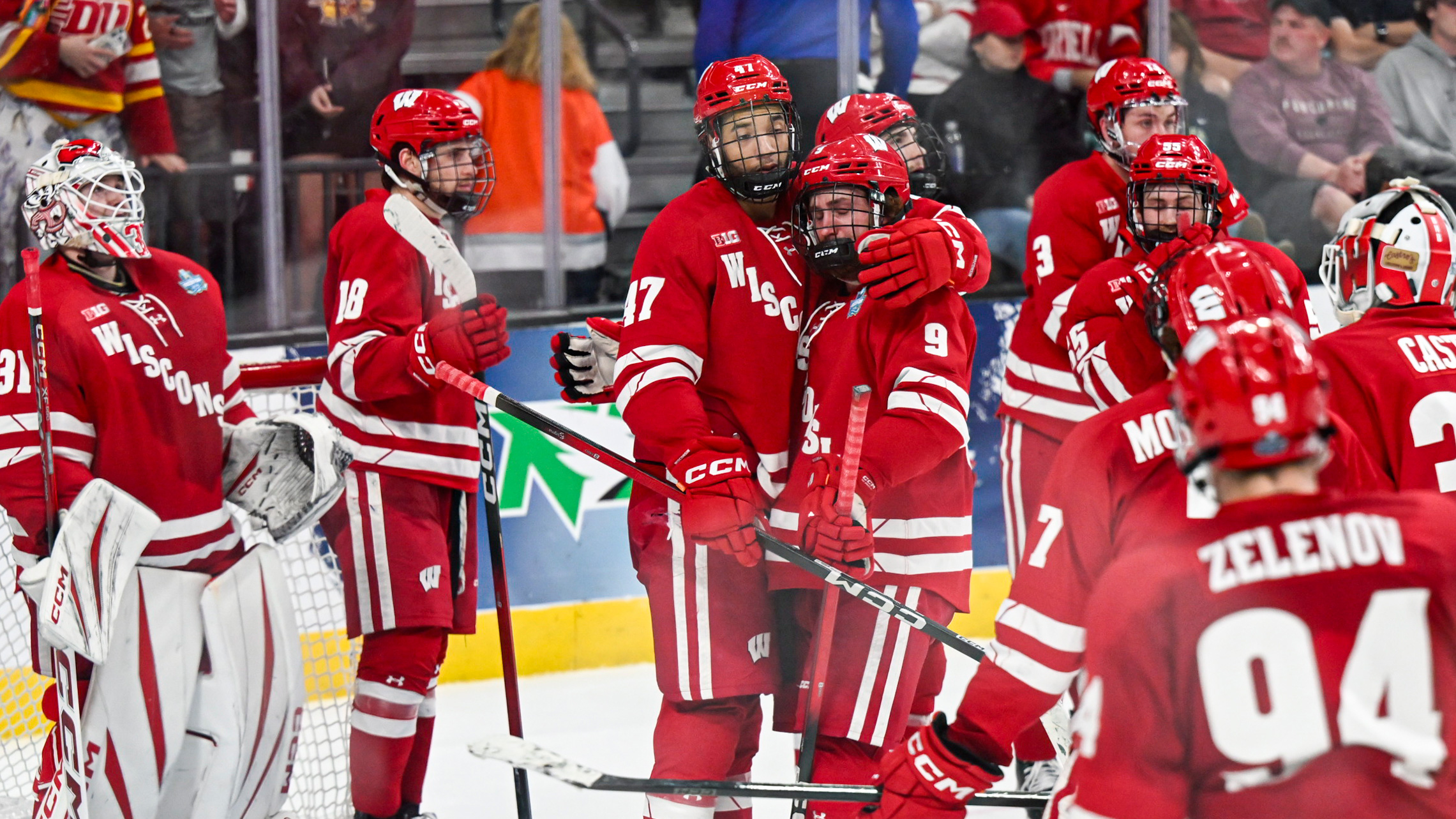 Wisconsin players in red gather and hug each other in defeat.