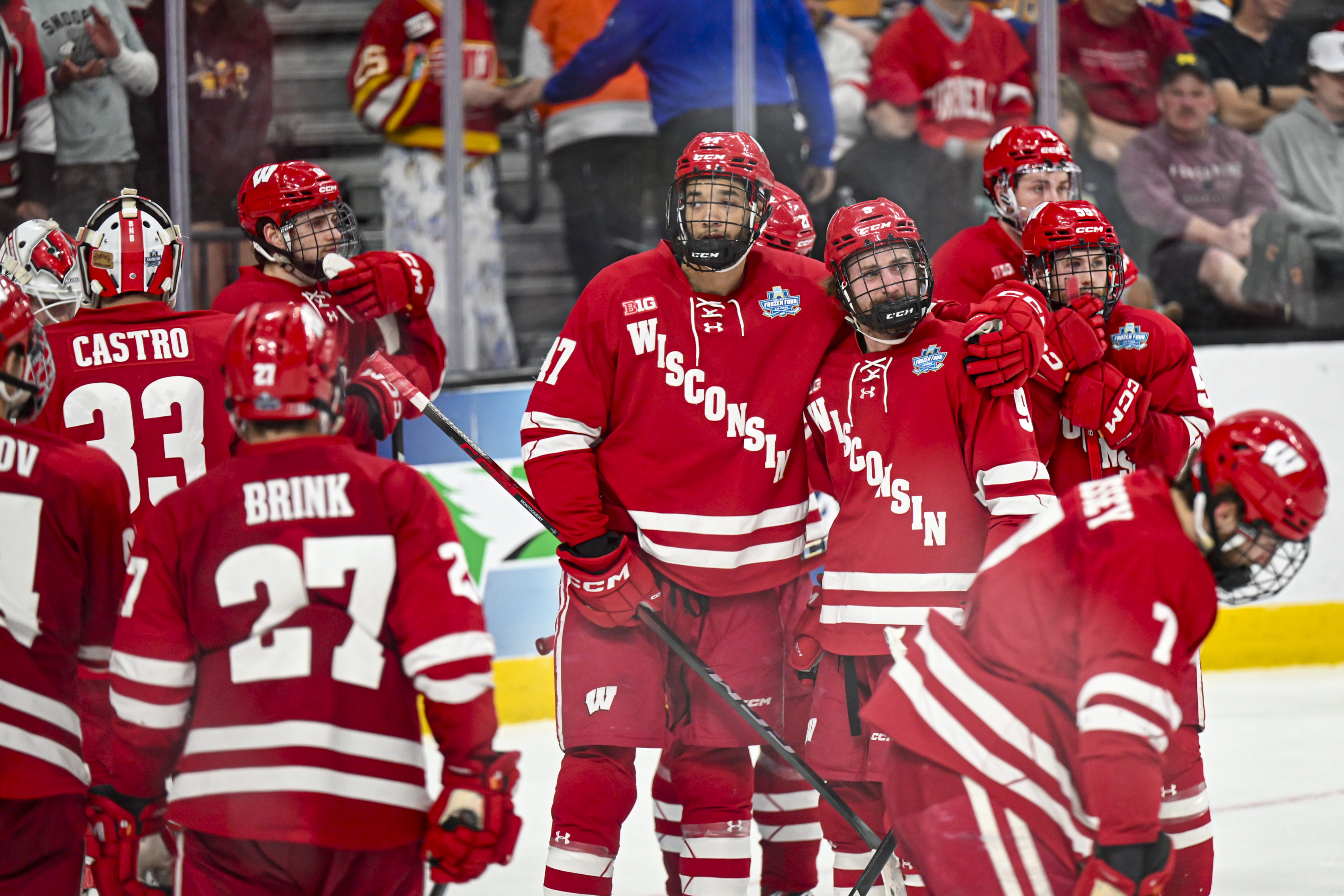 Wisconsin players in red gather and hug each other in defeat.