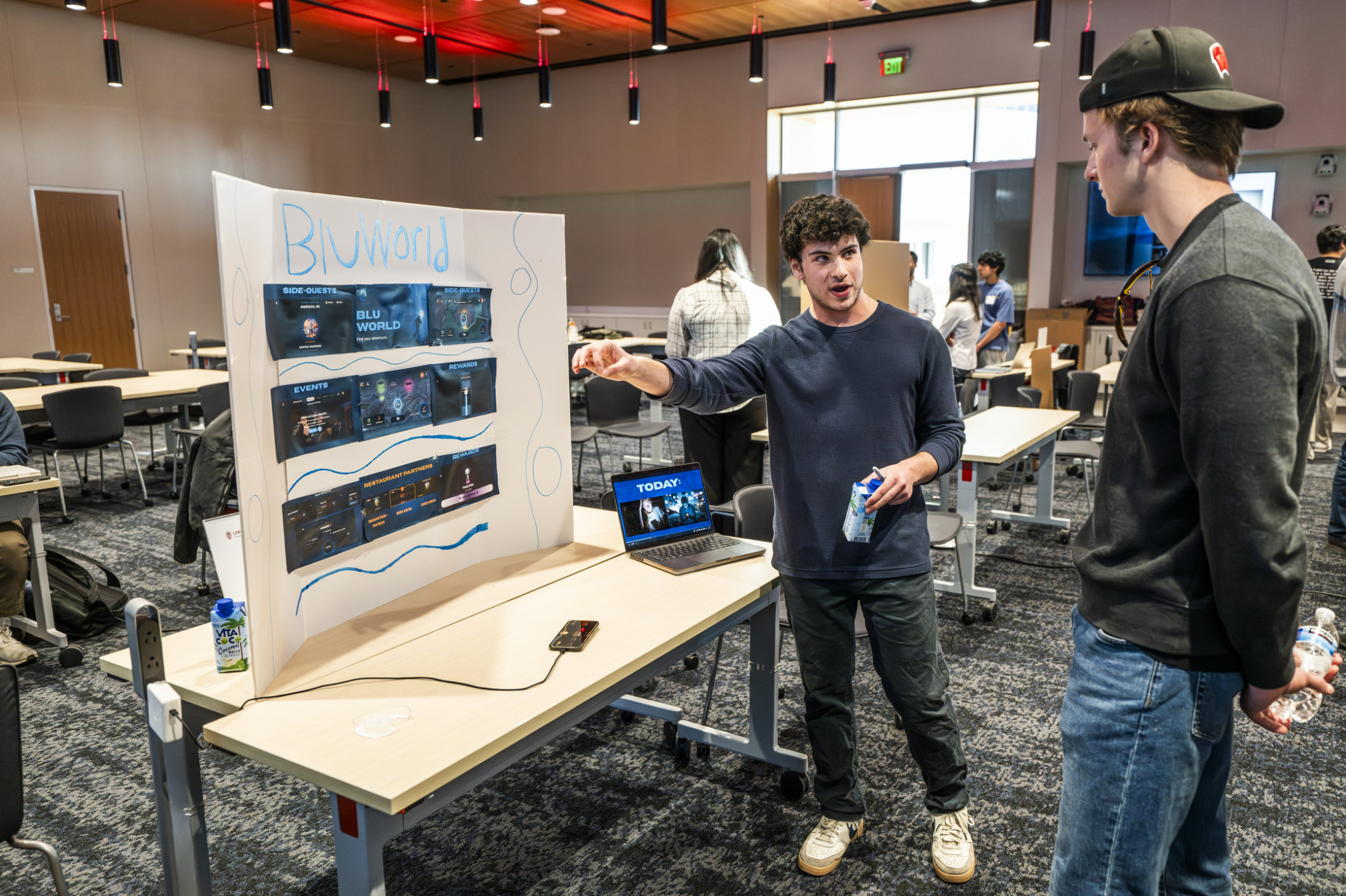 Two people talk in front of a research poster.