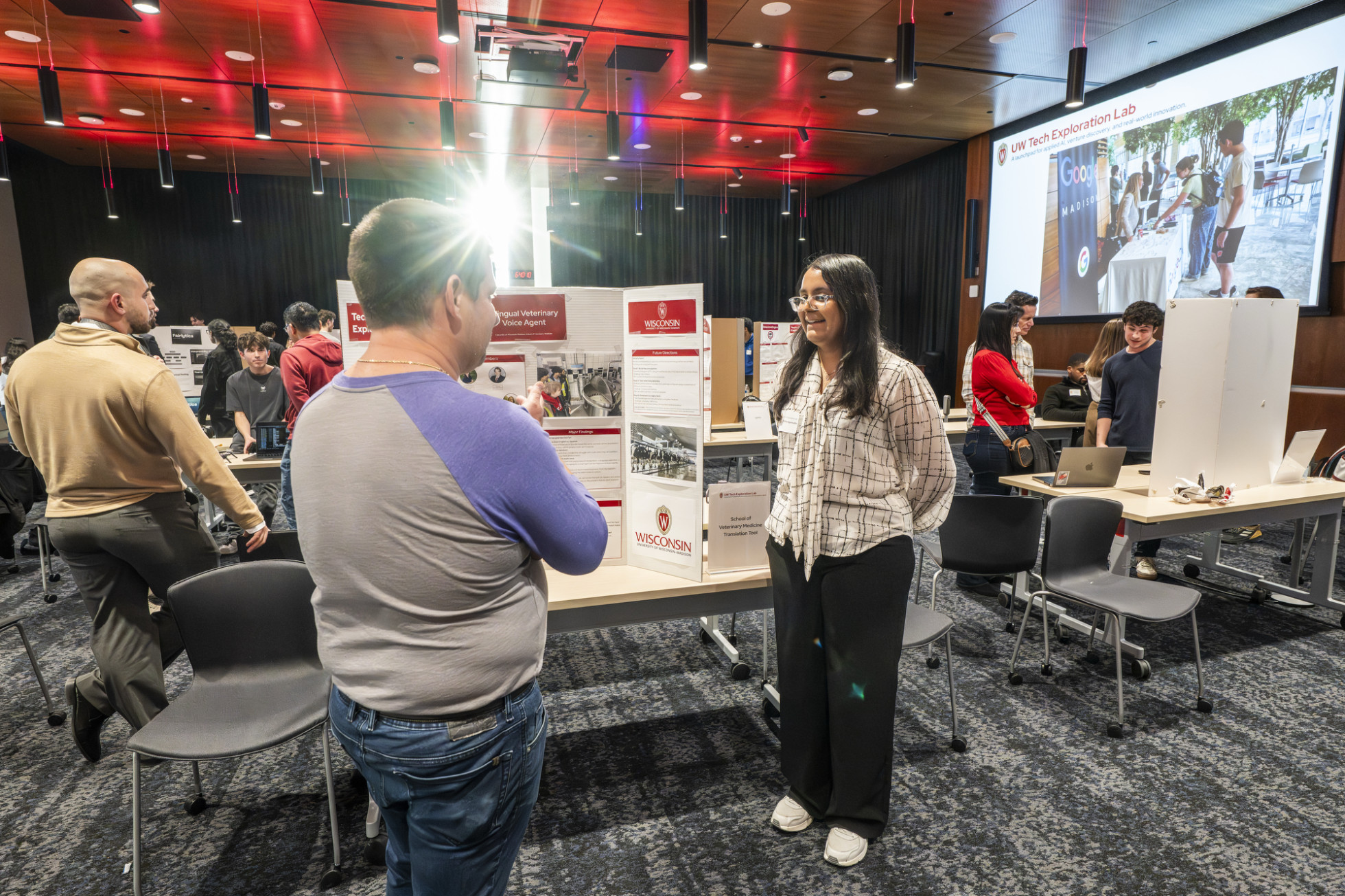 Two people talk in front of a research poster.