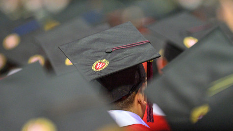 Graduates wearing black mortarboards seated at a graduation ceremony.