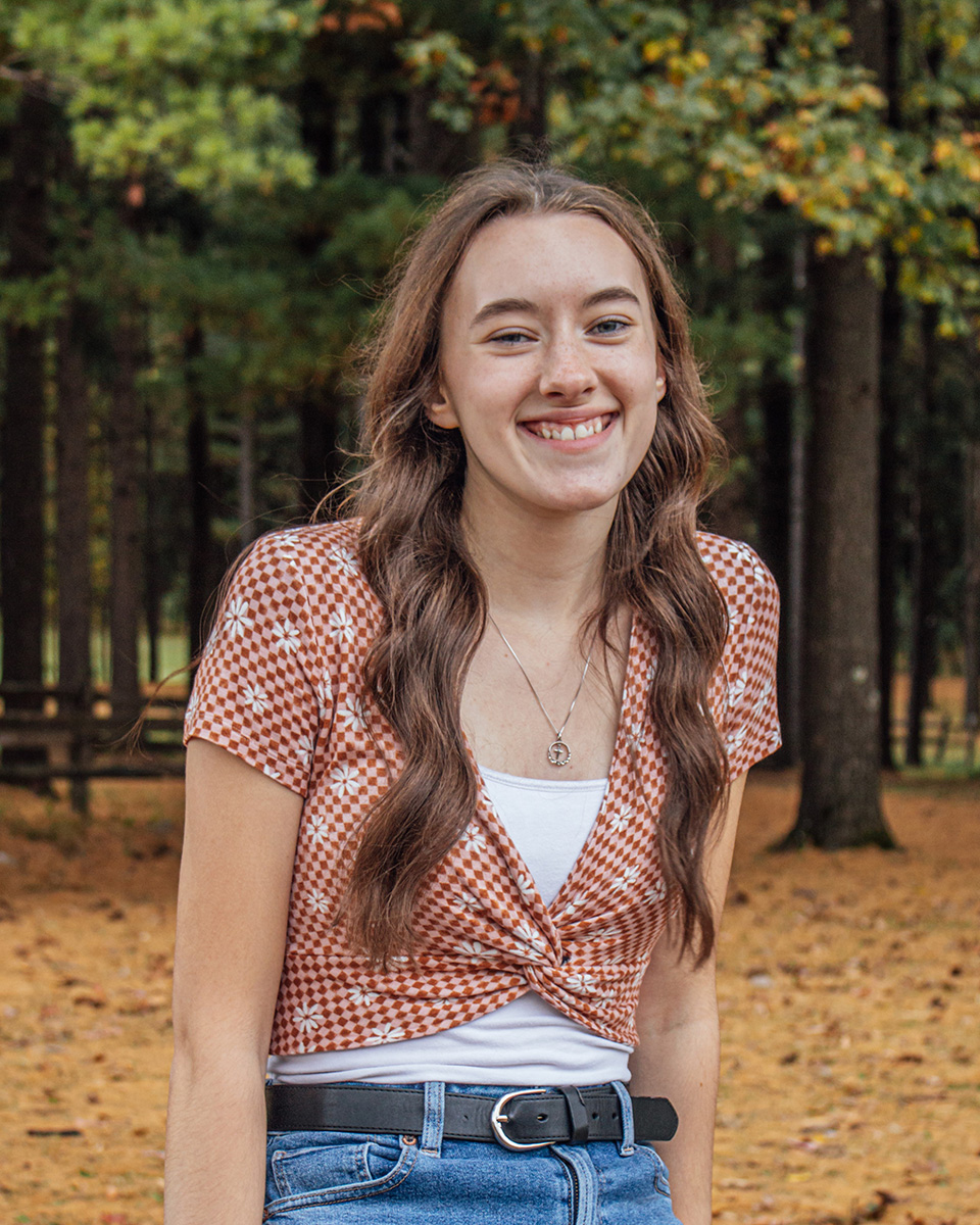 Photo of Caitlin Proffitt, outdoors, with trees in the background.