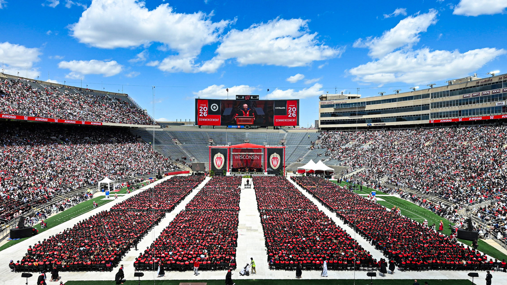  Surrounded by a nearly clear, blue sky, Spectators and graduates fill Camp Randall Stadium 