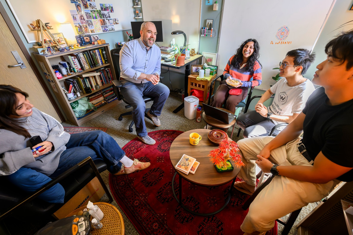 Brendan Eagan meets with a group of undergraduate research interns in a nicely furnished office. 
