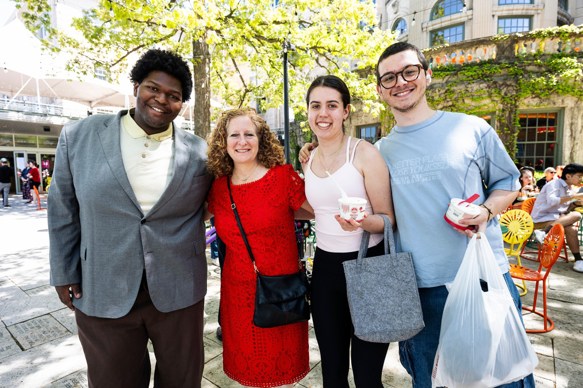 Mnookin, wearing a red dress in honor of the Wisconsin Badgers, links arms and poses for a picture with event guests.