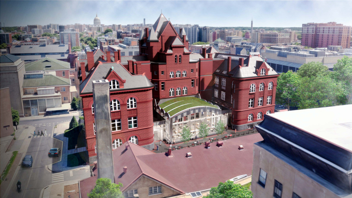 A computer-generated image of a large red brick building on a university campus. The rendering includes a windowed atrium on the back of the building. The top of the atrium supports plant-life.