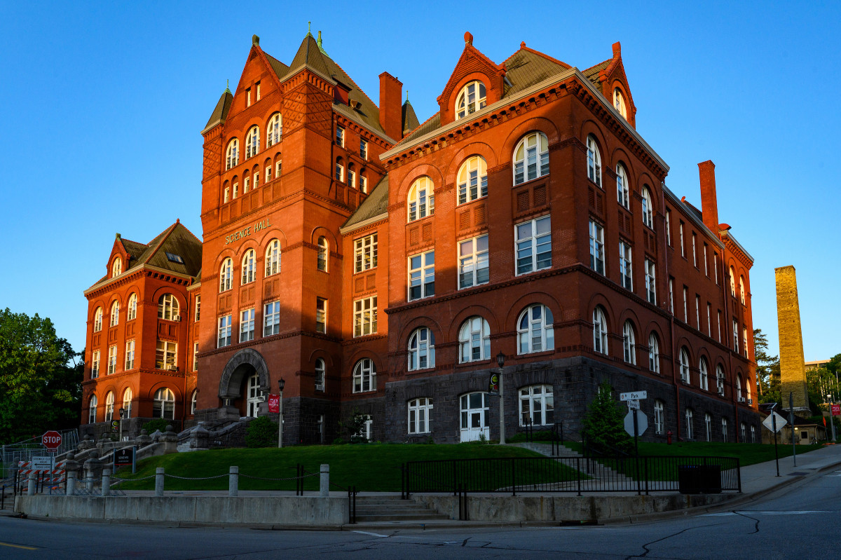 A large red building with many white-framed windows. There is a shaft of sunlight cast across part of the building, which is set against a oure blue sky.