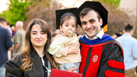 A person in graduate attire pictured with a child and another adult