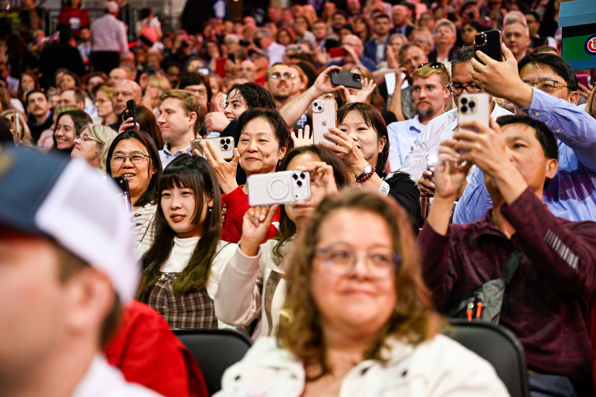 Family and friends of graduates in the crowd smile and take pictures from their phones. 