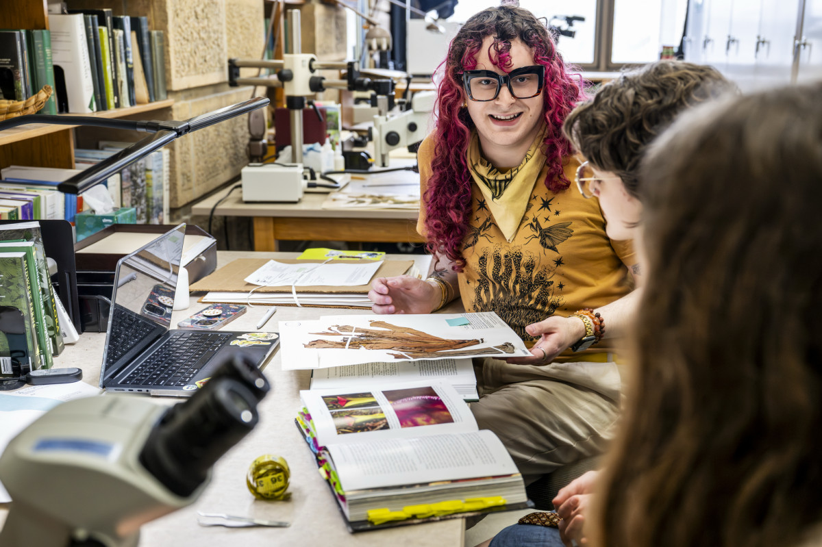 Joseph Walston reviews publications at a desk alongside two undergraduate students. 