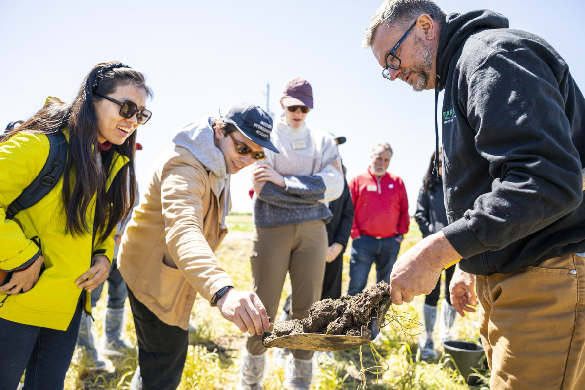 Koepke holds a shovel of dirt for tour members to touch.
