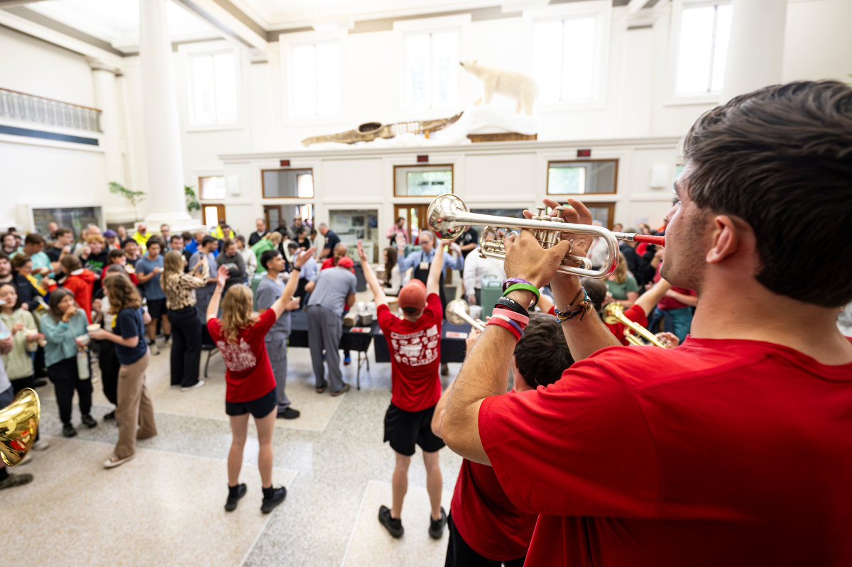 The UW Marching band, all wearing red, plays a song for the large group of employees who wait for ice cream in the lobby of Birge Hall.