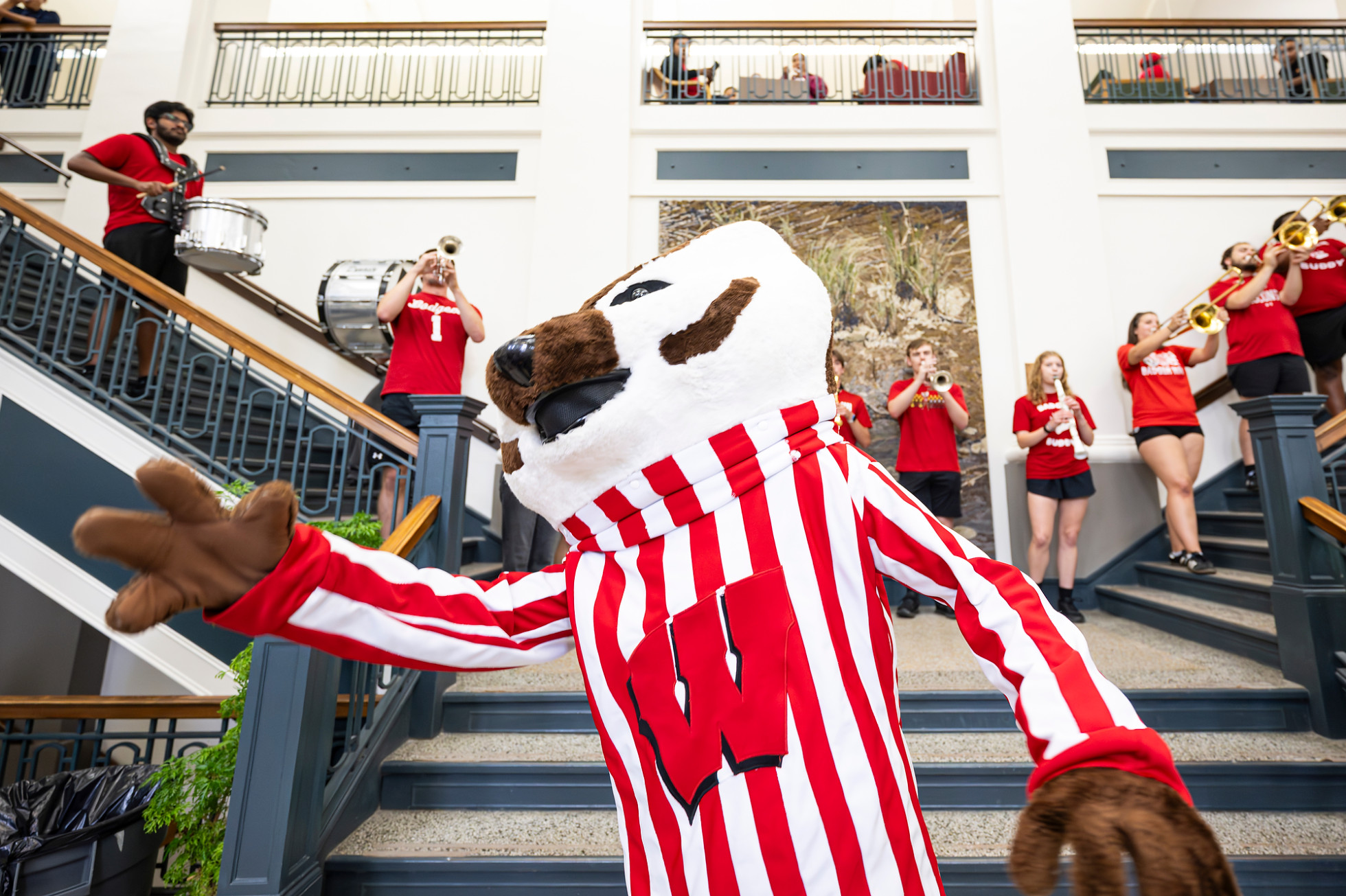 Mascot Bucky Badger dances at the bottom of a staircase in Birge Hall.