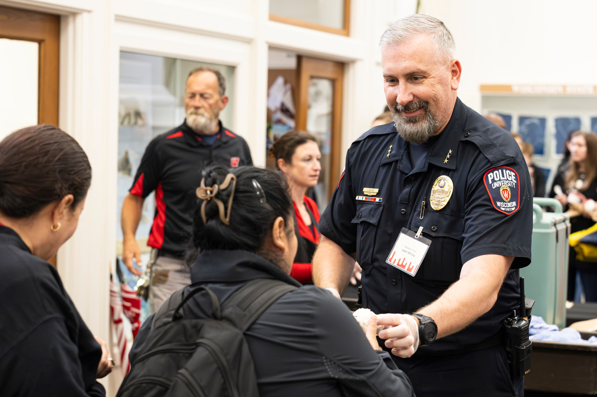 Whitney wears his UW Police uniform and serves a scoop of ice cream to an employee.