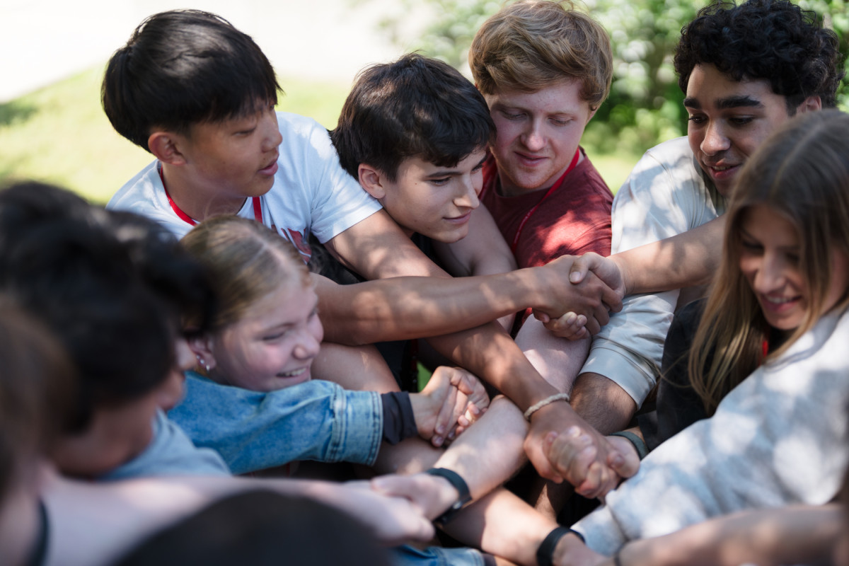 A group of UW–Madison students hold hands and tightly cluster together during an ice breaker exercise. 