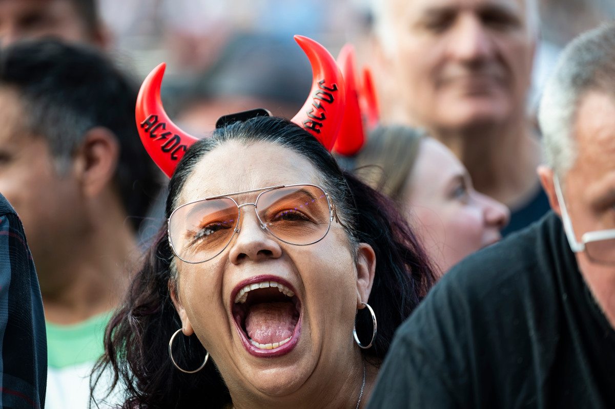 A fan wears a headband with light-up devil horns as she cheers for the band.
