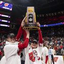 Two UW Badger womens volleyball players hoist the NCAA Championship trophy.