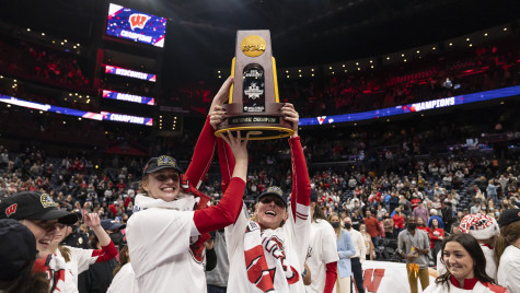Two UW Badger womens volleyball players hoist the NCAA Championship trophy.