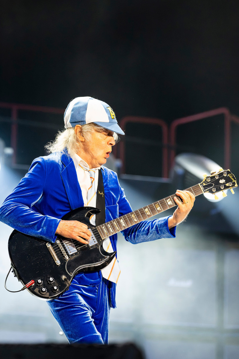 Wearing a blue velvet suit and a baseball cap, AC/DC guitarist Angus Young performs on stage