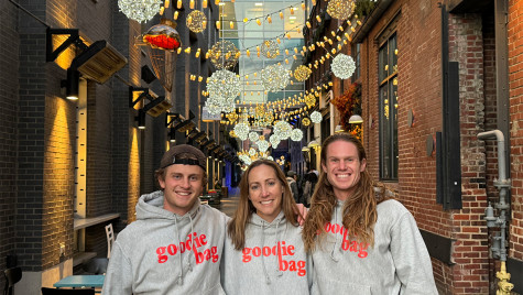 Three people wearing sweatshirts that read Goodie Bag pose for a picture.